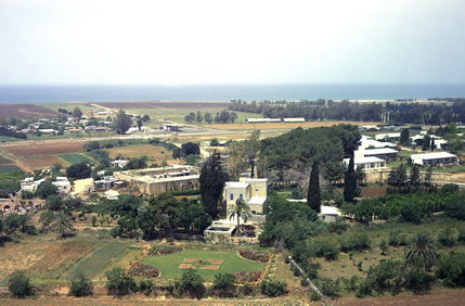 An aerial photograph of the village of Mazra‘ih showing the mansion where Bahá’u’lláh lived. The Mediterranean Sea is in the distance.